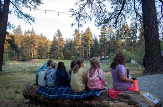 Girls sitting on log.