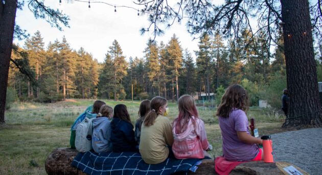 Girls sitting on log.