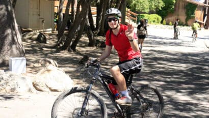 Boy waving riding a bike.