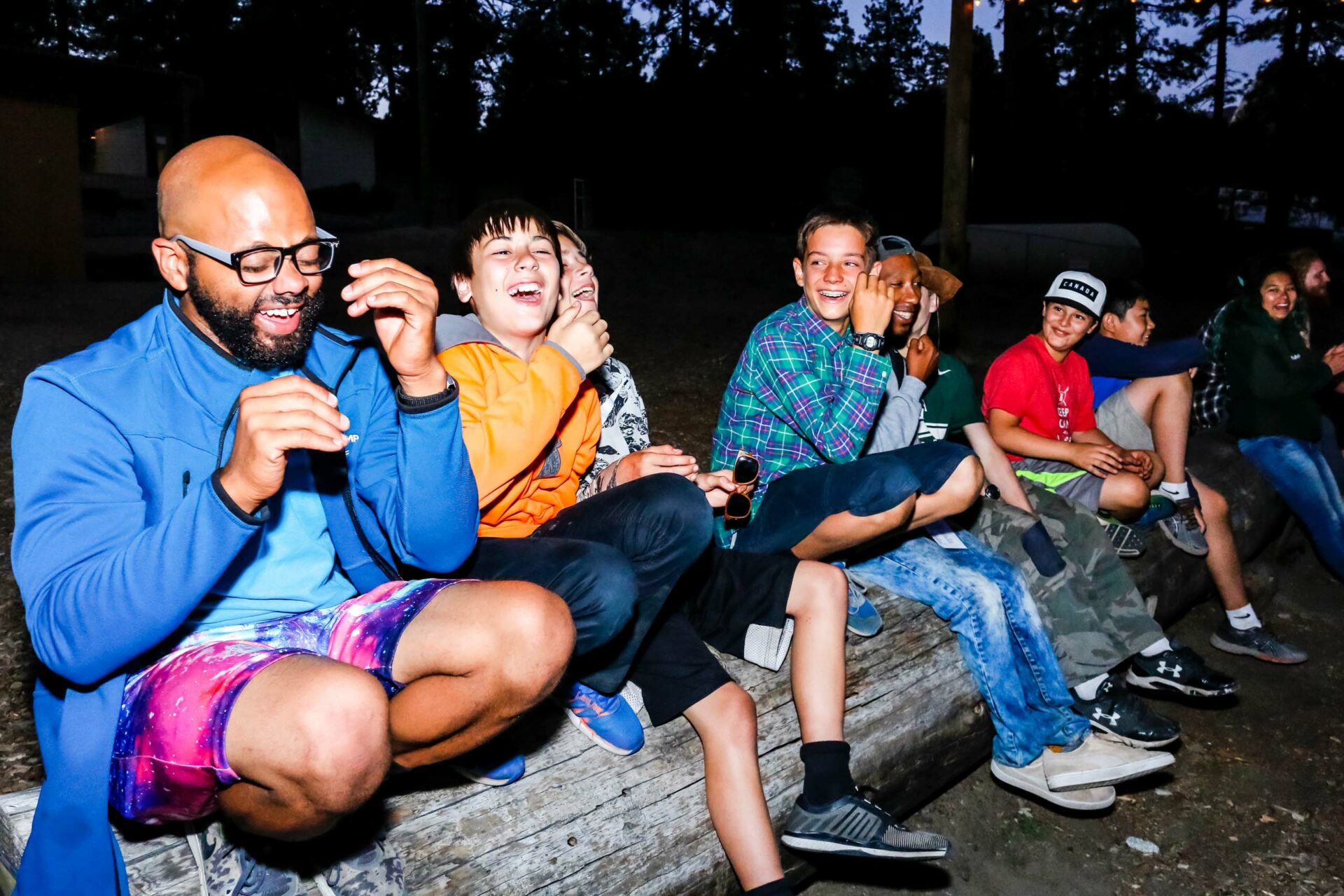 People sitting on log laughing.