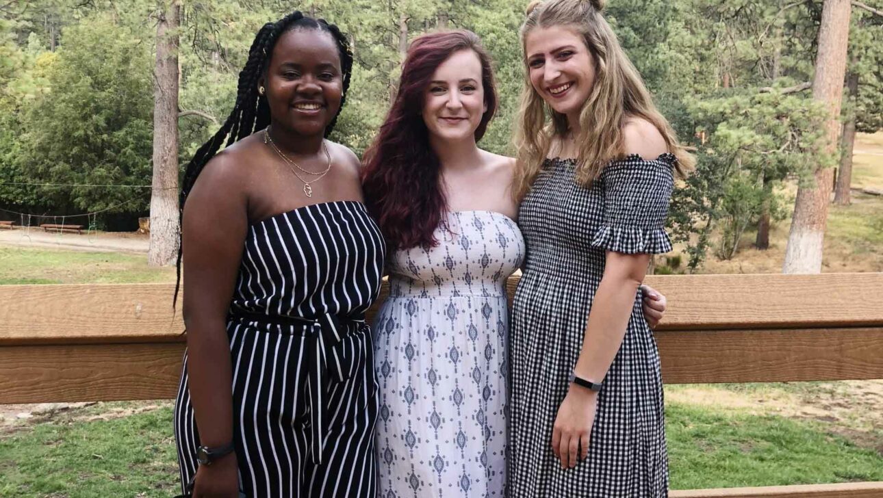 Three girls standing smiling.