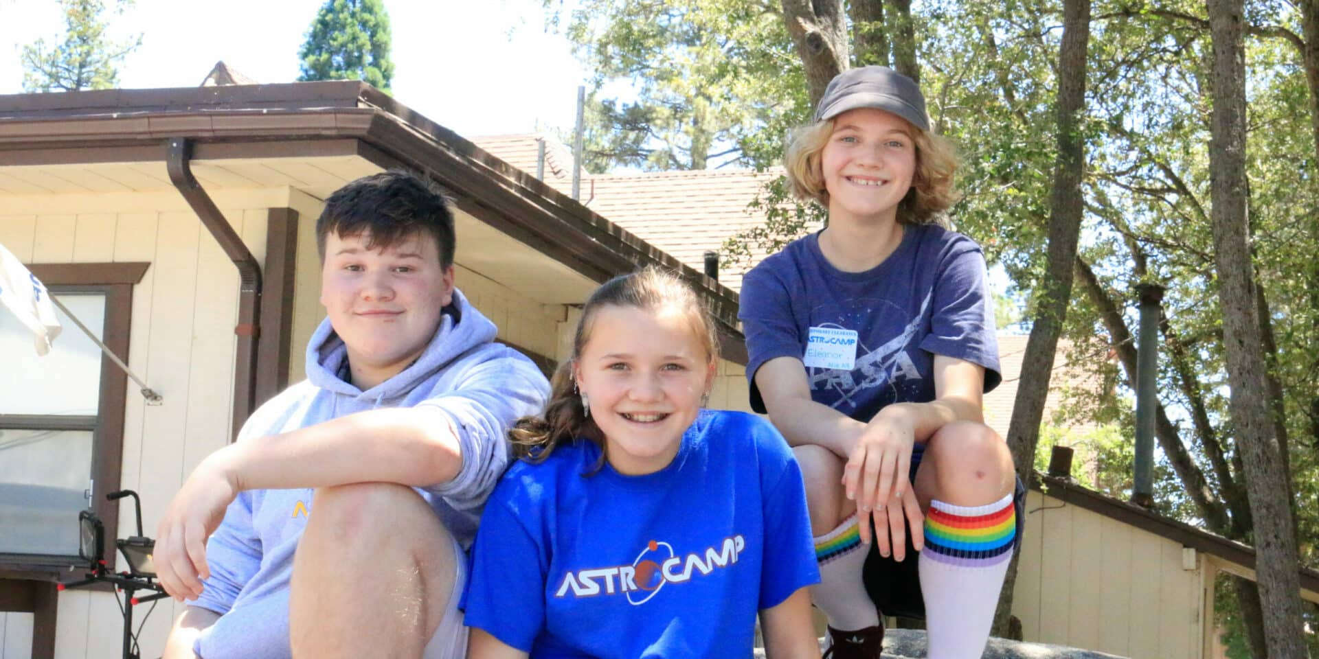 Three kids sitting on rock.