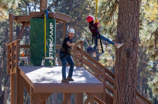 Instructor pulling kid on zipline.